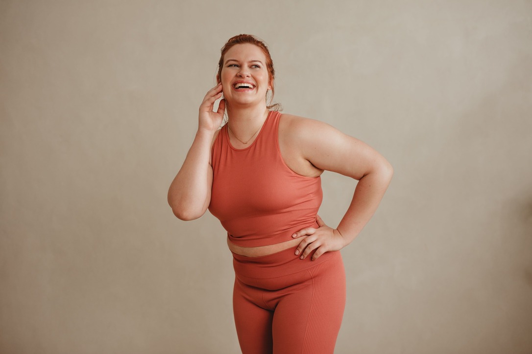 Confident Woman In Sportswear Looking Away And Smiling. Healthy Plus